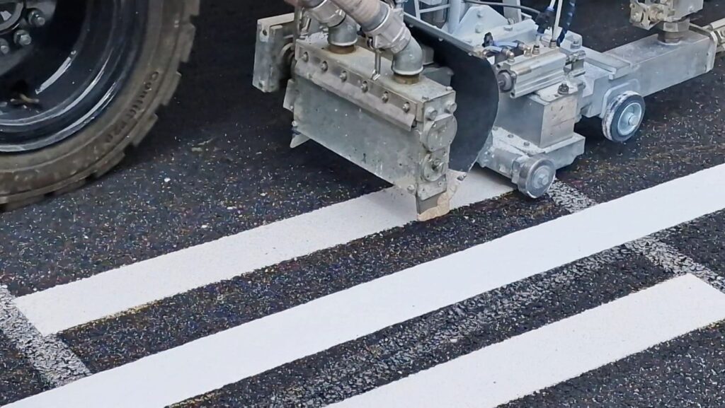Fahrbahnmarkierungen werden von einem Arbeitsfahrzeug auf Asphalt aufgetragen